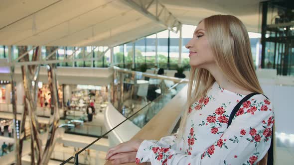 Cheerful Woman Greeting Acquaintance in Mall. Side View of Lovely Young Female Smiling and Waving