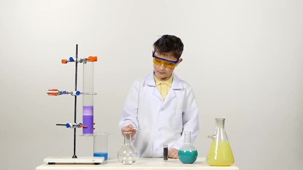 Little Boy Chemist in Uniform, Protective Glasses Has Successfully Tested the New Formula and