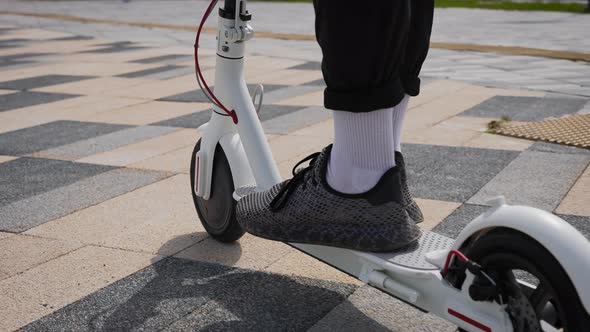 Men's Feet in Sneakers on an Electric Scooter