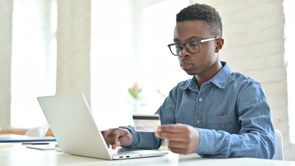 Successful Online Payment by African Man on Laptop 