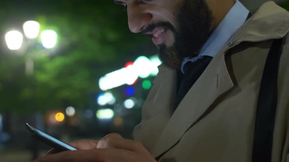 Smiling Middle Eastern man texting on smartphone