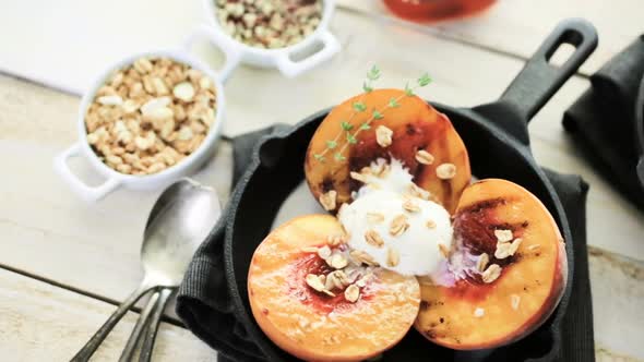 Organic grilled peaches with scoop of vanilla ice cream on a cast iron frying pan.