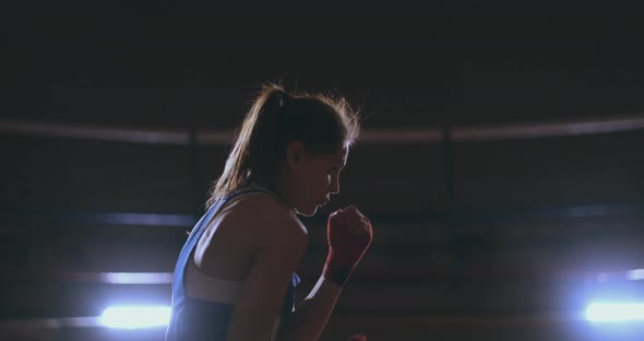 Professional Beautiful Female Boxer Shoots Off Conducting a Shadow Fight in a Dark Hall Room in Slow