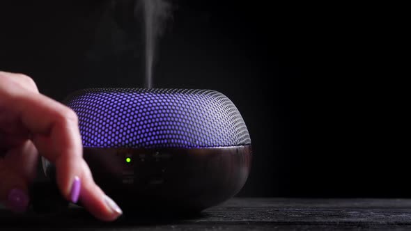 Woman Add Essential Oil Into Diffuser on Black Wooden Table