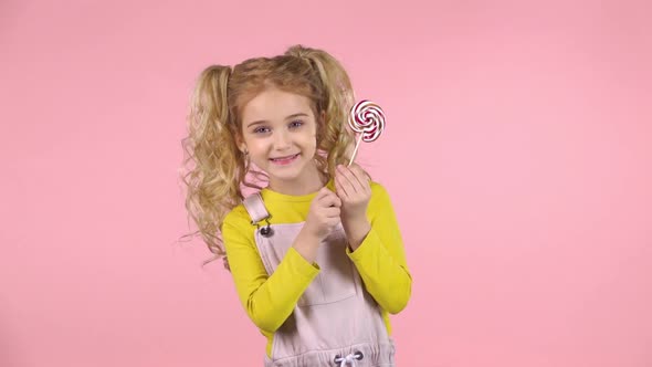 Little Blond Female Is Palying with Lollipop and Smiling. Slow Motion