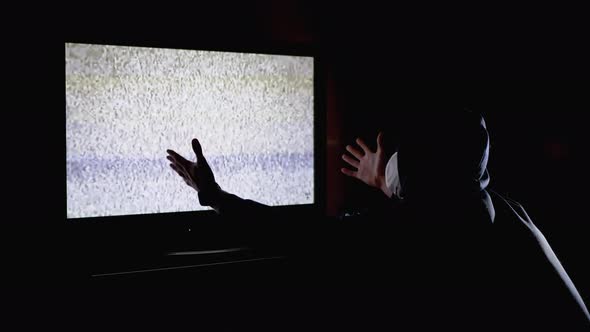 Silhouette Man in Hood and Medical Mask Watching TV Interference with Hands Up