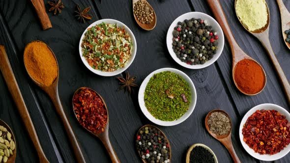 Dry Colorful Spices in Spoons and Bowls with Fresh Seasoning on Dark Background Top View
