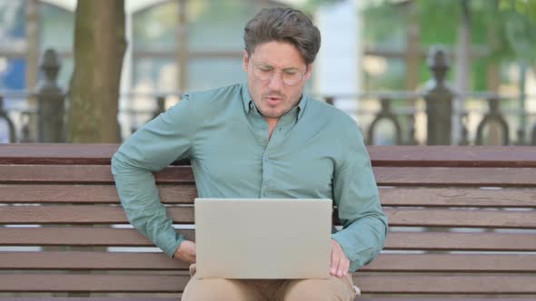 Middle Aged Man having Back Pain while using Laptop, Outdoor