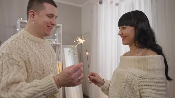 Smiling Happy Young Husband and Wife Holding Sparklers and Talking in Slow Motion on New Year's Day