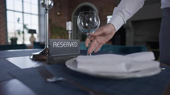 Male Hand Putting Drinking Glass on Table with Reserved Sign