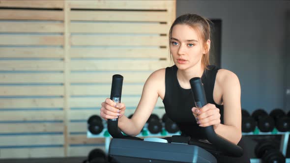 Pretty Woman in the Gym Exercising Her Legs Doing Cardio Training on Bicycle