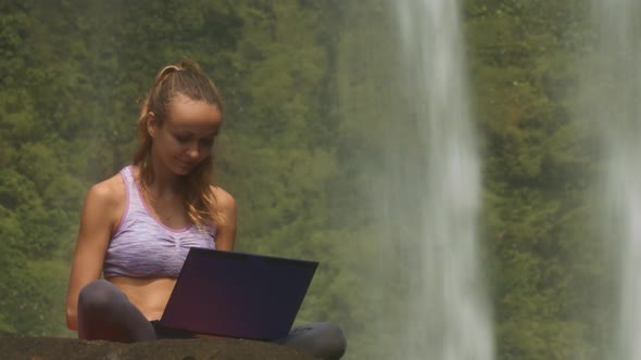 Girl Smiles Opens Laptop Starts Typing at Waterfall