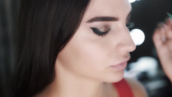 Artist Applying Makeup to the Eyes of Beautiful Young Caucasian Brunette