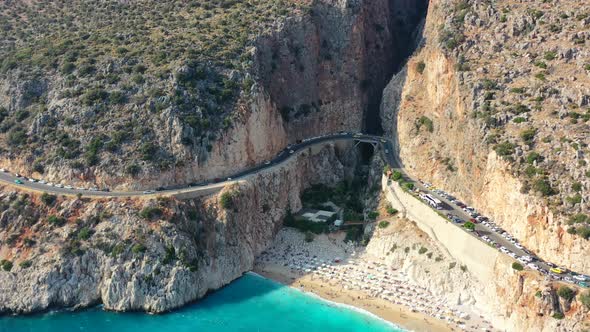 aerial drone panning left during a sunset afternoon at Kaputas Beach in Kas Turkey as cars drive alo