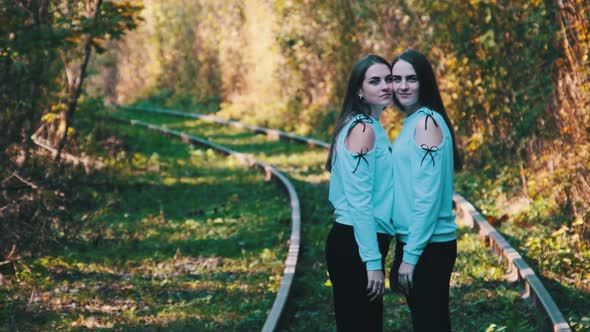 Smiling Young Twins Women Standing Together on Railroad