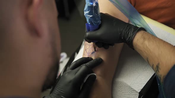 A Closeup of a Tattoo Artist Makes a Tattoo on a Woman's Arm