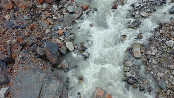 Aerial View of a Stormy Mountain River Among Multicolored Stones