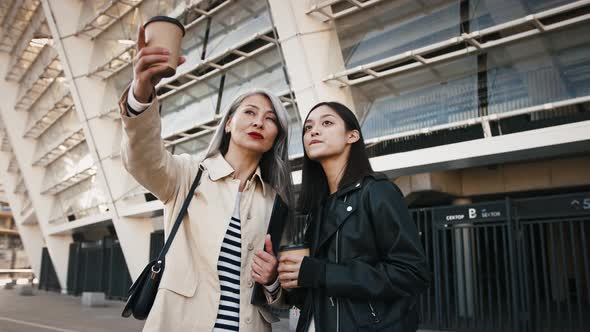 Asian Mature Female is Holding Folder and Paper Cup of Coffee Discussing Business Plans with