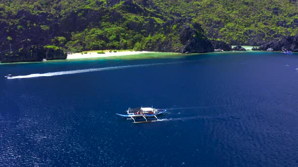 Aerial Drone View of White Traditional Filipino Boat Floating on Top of Clear Blue Water Surface
