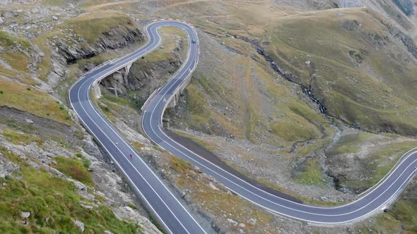 Aerial view of two runners running along a road in Transfagarasan mountain, Romania. Athletes far aw