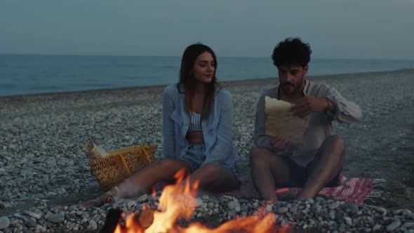 Young Couple at the Bonfire on the Beach