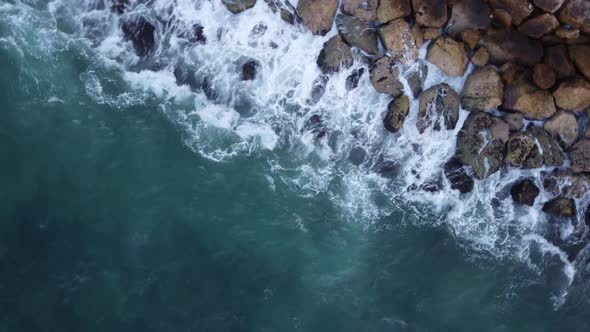 Waves crash on the breakwater as the drone rotates