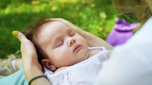 Lovely Newborn Baby Sleeping on Lap Caring Mother Outside