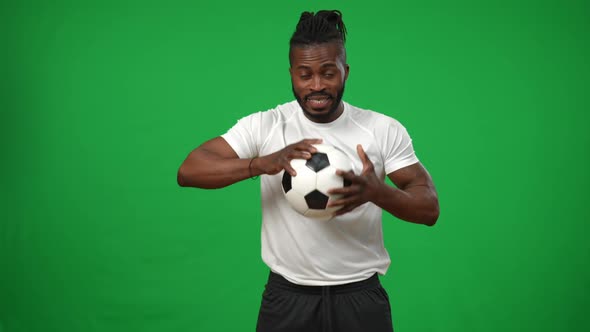 Focused African American Man Holding Football Ball Looking at Camera with Serious Facial Expression