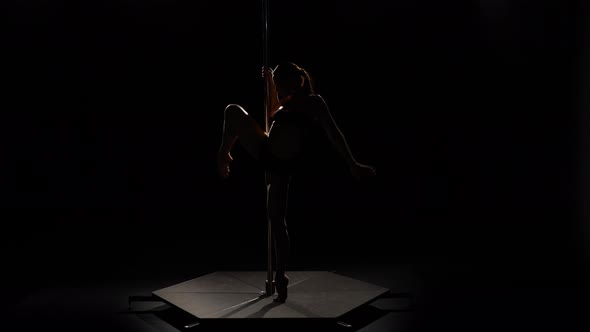 Girl Spinning on the Pole. Black Background. Silhouette