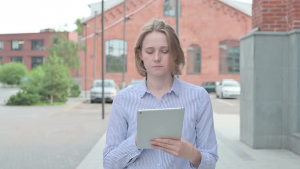 Woman Using Tablet While Walking in Street