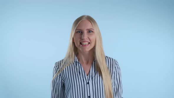 Excited Blonde Woman Yelling and Raising Fists in Cheer on Blue Background