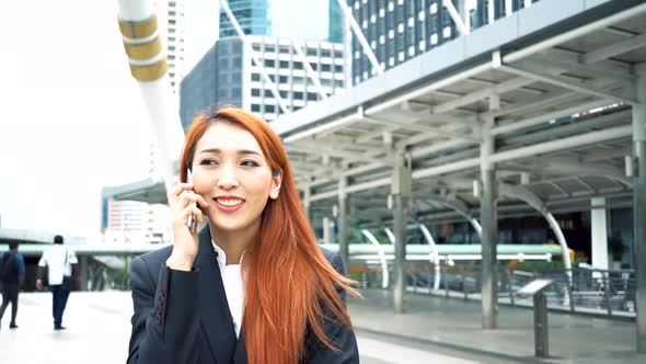 Young Business Woman Talking on Mobile Phone and Walking with Smiling Over Building Background