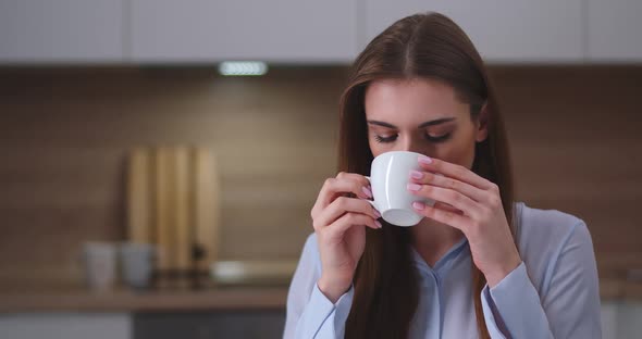 Young Beautiful Female Sitting in the Kitchen and Drinking Tea, Portrait, Day Off at Home.