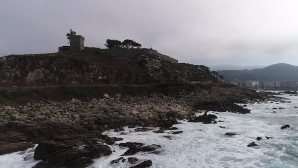 Drone flight above the waves clashing on the rocks in Baiona, Galicia, Spain