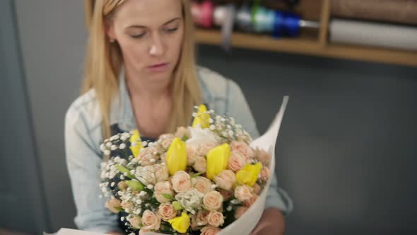 Young Blonde Female Florist Wrapping a Bunch of Flowers in Decorating Paper