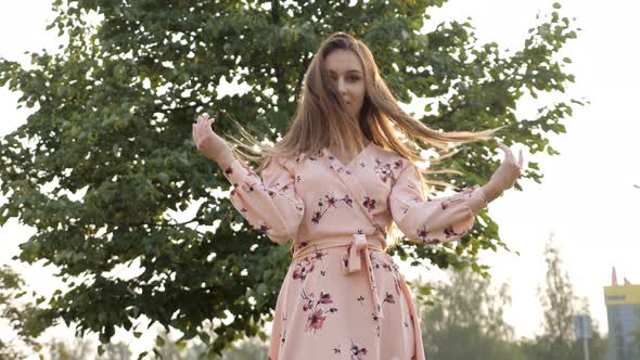 Woman with Loose Fair Hair in Pink Dress Smiles and Poses