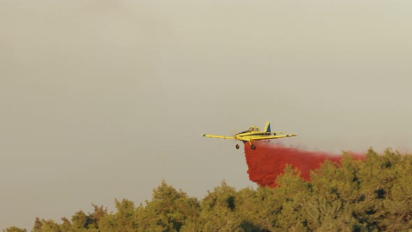 Fire fighter plane drops fire retardant on a forest fire in the hills