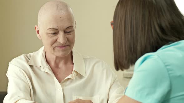 An Elderly Woman with Cancer Bald After Chemotherapy Consults with an Oncologist