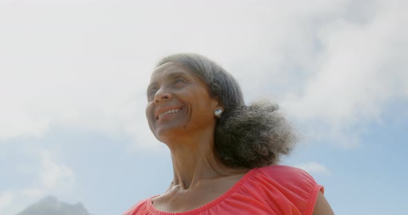 Low angle view of active senior African American woman stretching her arms in sunshine on the beach