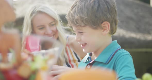 Happy caucasian mother and son having dinner and talking in garden