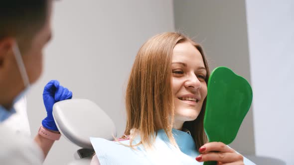 Young Woman Looking at Her Teeth After Successful Dental Treatment