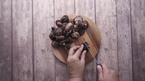 Hand Cutting Raw Champignon Mushroom on a Chopping Board on Table