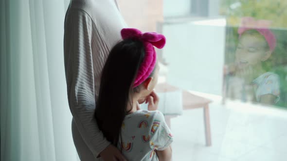 The girl laughs at the tickles of her mother