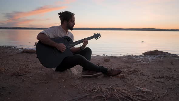 Silhouette of a Young Man on the Beach with a Guitar Playing Chords By Torrevieja Pink Lake in