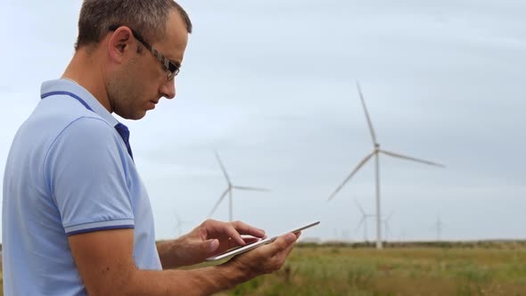 A Male Wind Farm Engineer Works on a Tablet. Production of Clean Electricity
