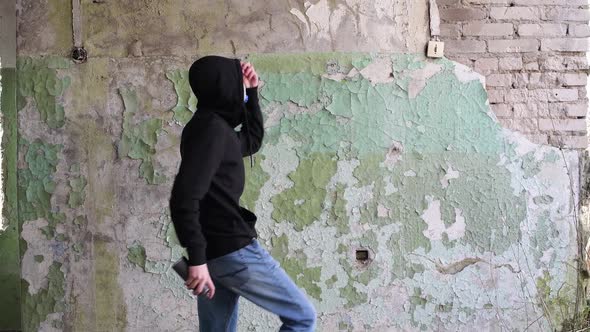A guy walks past a shabby wall, inscribes, putting on a respirator and moves on