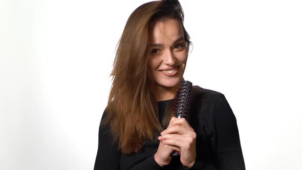 Singing girl isolated on background. Portrait of funny young girl singing in comb