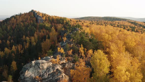 Aerial View of a Cliff Surrounded By a Colorful Autumn Forest at Sunset