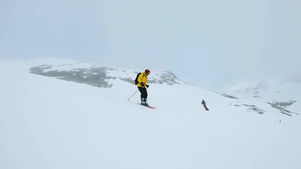 Man in yellow jacket ski's down a mountain on a cloudy day in Laax, Switzerland