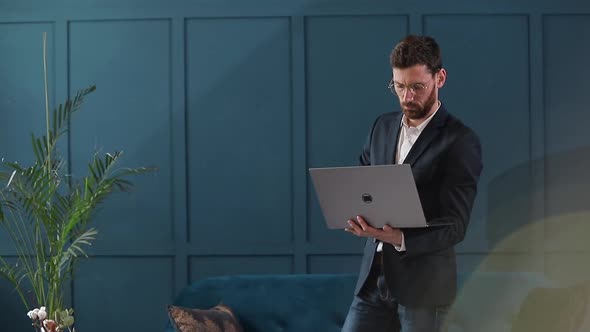 Portrait of an Elegant Businessman with Laptop at the Luxury Blue Office Interior.